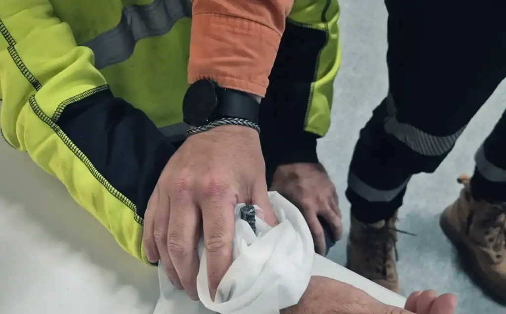 Worker treating hand injury with cloth.
