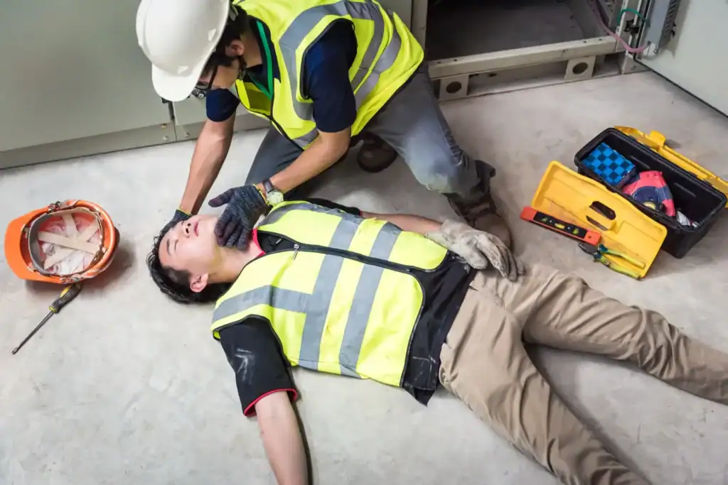 Worker providing first aid to injured colleague on floor.