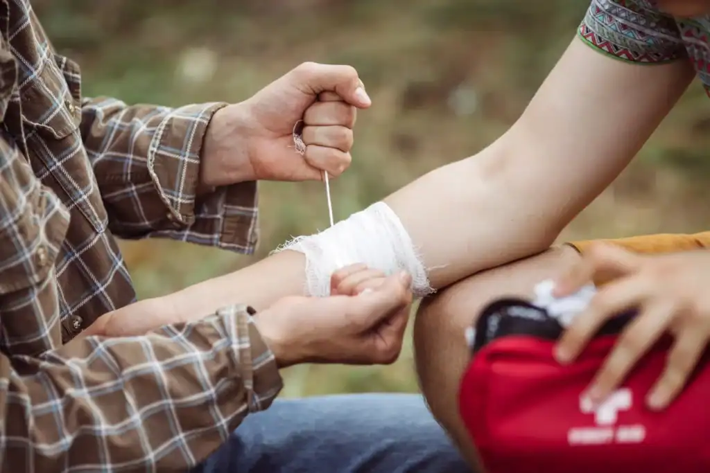Applying bandage to injured arm outdoors.